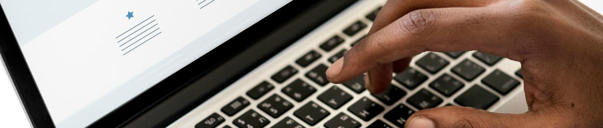 Close-up image of a hand typing on a laptop keyboard